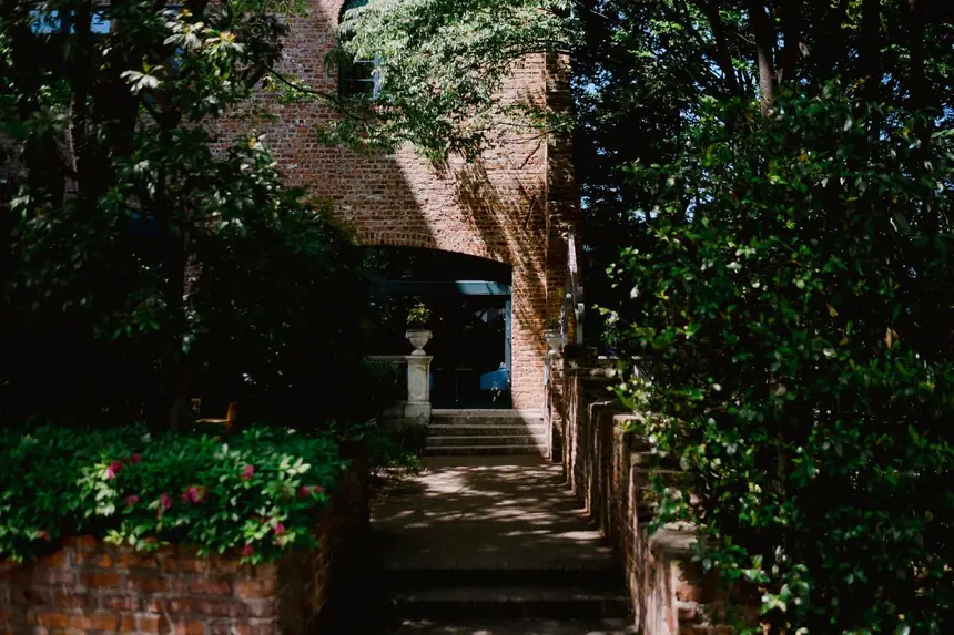 Brick house entrance with low retaining walls and steps rising from the driveway to the front door