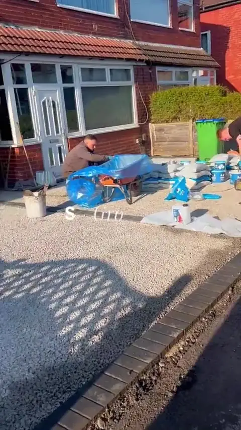 S P Groundworks team mixing resin and aggregate on a driveway outside a red brick semi in Middleton